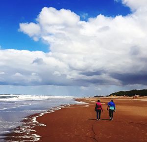 Rear view of people walking on beach