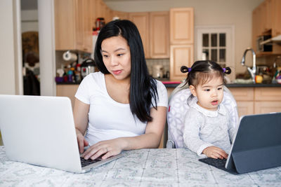 Mother and daughter using laptop at home