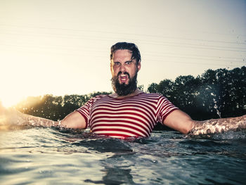 Portrait of bearded man swimming in sea against sky