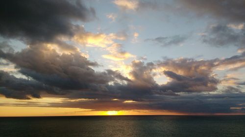 Scenic view of sea against cloudy sky at sunset