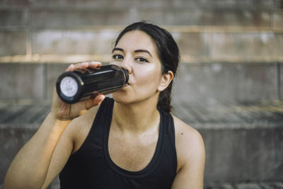 Portrait of woman drinking water from bottle
