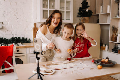 Mom, daughter and son prepare festive christmas food according to the recipe using a mobile phone
