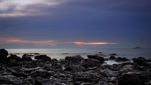 Rocks by sea against sky during sunset