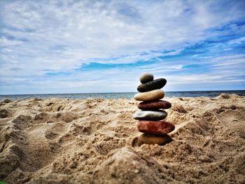 Stack of pebbles on beach against sky