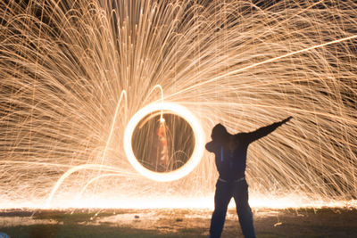 Full length of silhouette man standing against illuminated wire wool at night