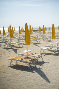 Lounge chairs and parasols on beach against sky