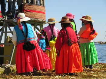 Rear view of people in traditional clothing standing by lake