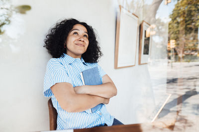 Contemplative woman with tablet pc leaning on wall at cafe