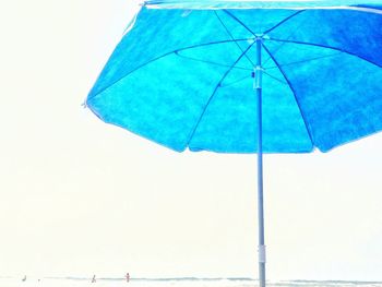 Blue umbrella on beach against clear sky