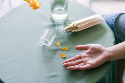 Cropped hand of woman holding pills on table