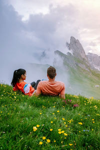 People sitting on mountain against sky