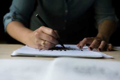 Cropped image of woman drawing on paper at table