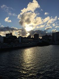 Sea by buildings against sky during sunset