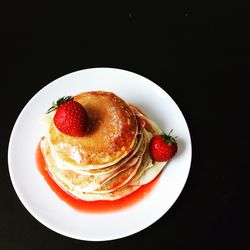 Close-up of dessert served in plate against black background