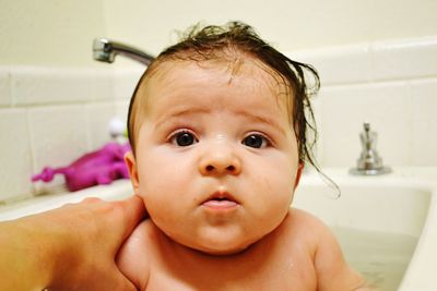 Cropped hand of mother holding daughter in bathtub at bathroom