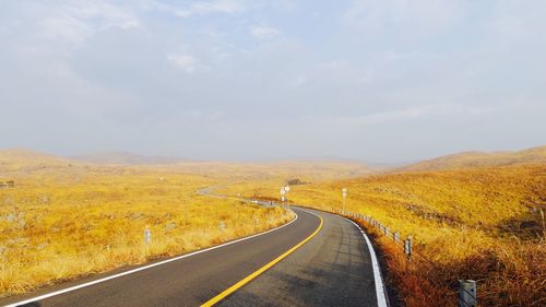 Empty road along landscape against sky