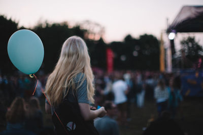 Woman with helium balloon enjoying music concert during sunset