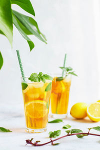 Iced iced tea in a glass with a straw, mint leaf and lemon slices inside. cool drinks in the heat. 