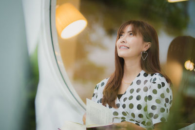 Young woman looking away while reading book