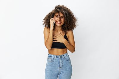 Portrait of young woman standing against white background