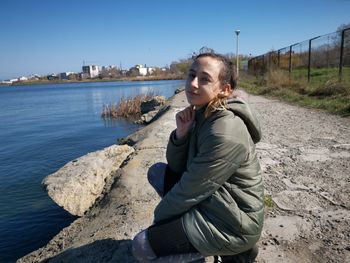 Portrait of girl at lakeshore against clear sky