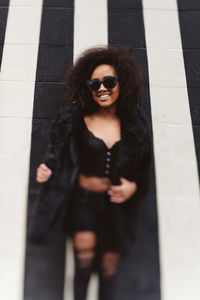 Portrait of young woman wearing sunglasses standing outdoors