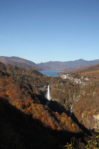 Scenic view of sea by mountain against clear sky