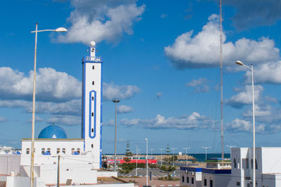 Tower amidst buildings against blue sky