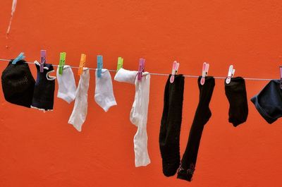 Socks drying on clothesline against orange wall