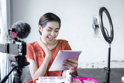 Young woman using phone while sitting on table