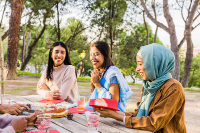 Smiling young woman enjoying food with friends