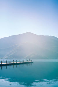 Scenic view of sea and mountains against clear blue sky