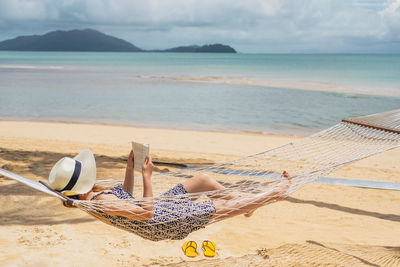 Woman lying on sand at beach against sky