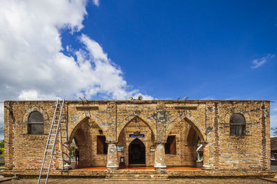 Facade of old building against cloudy sky