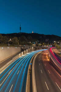 High angle view of light trails on road against blue sky