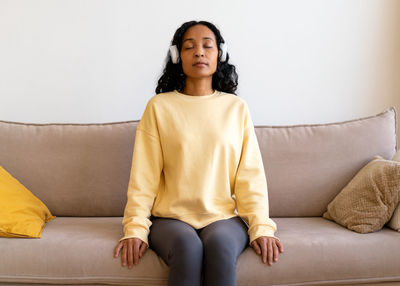 Portrait of young woman sitting on sofa at home