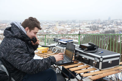 Side view of young man holding cityscape