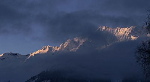 Low angle view of snow covered mountains against sky