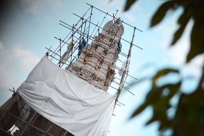 Low angle view of white temple under construction against sky. 