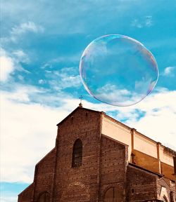 Low angle view of bubble and church against blue sky