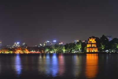 Illuminated buildings by river at night