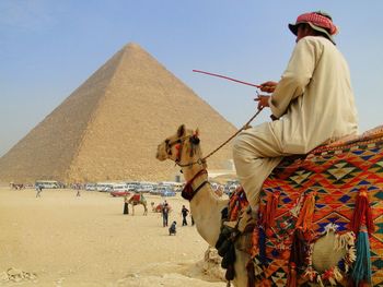 Rear view of man and woman standing in desert against clear sky