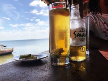 Glass of bottles on table against sky