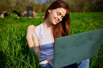 Young woman using laptop at park