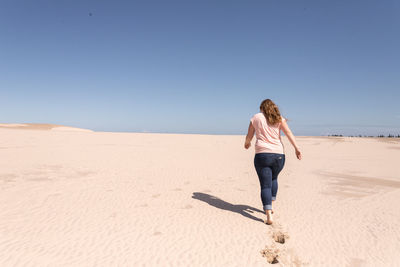 Full length of woman on sand at beach against clear sky