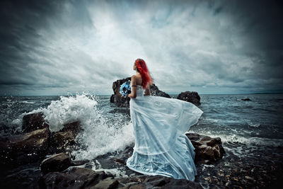 Rear view of woman on beach against sky