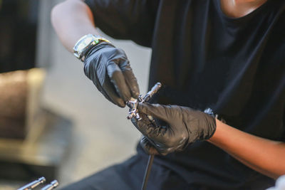 Midsection of man repairing equipment in workshop