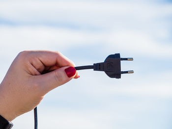 Close-up of person holding hand against sky