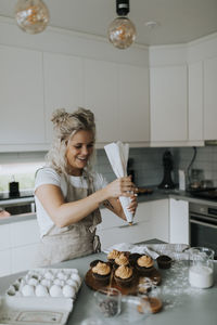 Woman putting icing on cupcakes