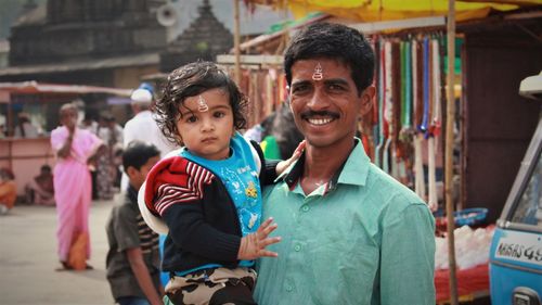 Portrait of father carrying toddler son on road in city